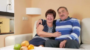 Sevgili eşi güzel bir evde bir kanepede kucaklayan mutlu komuta sizde. Onlar konuşmak ve gülmek. Kameraya bir gülümseme ile seyir