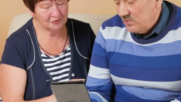 Feliz hombre y mujer mayores hablando en tableta PC en casa con los niños. Videollamadas a través de Internet ayuda a hablar con los familiares. Esposo y esposa en una hermosa casa — Vídeos de Stock