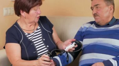 Yaşlı kadın evde kanepede kan basıncı ölçer. Zavallı adamın su kuyusu-varlık. Karısı kocası hakkında Bakımı