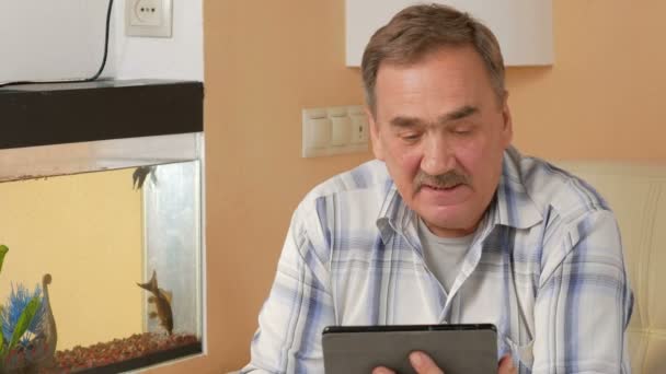 Ein älterer Mann mit Schnurrbart hustet und kommuniziert auf einer Videokonferenz mit einem Arzt. Arzt auf Tablet-PC gibt dem Patienten zu Hause Empfehlungen — Stockvideo