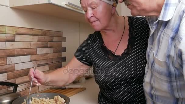 Mujer anciano marido da a probar el plato de la sartén. Él sopla en la cuchara y probar la comida cocinada. Los hombres como comida italiana cocida . — Vídeos de Stock