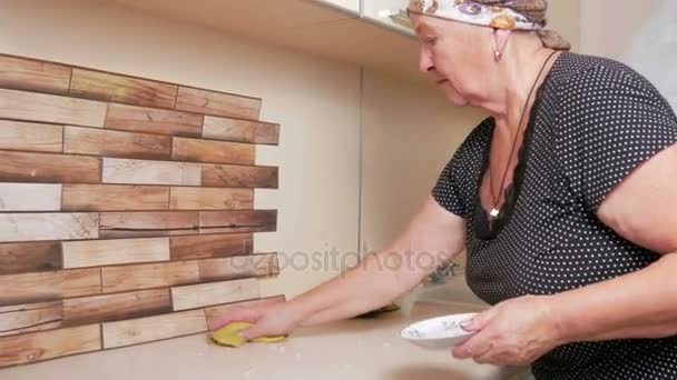 Vrouw ouder veegt de tabel doek. Zorgvuldig verzamelen kruimels en puin en gooit. zuiverheid huis concept — Stockvideo