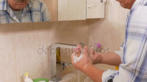 Homme âgé se lave les mains avec du savon dans le bain. Il se rince les mains avec de l'eau après traitement. Le concept de pureté — Video