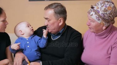 Büyük mutlu bir aile anne ve büyükanne ve büyükbaba eğlenceli evde kanepede bir bebekle. Gülmek ve kendi aralarında konuş. Aile mutluluk kavramı