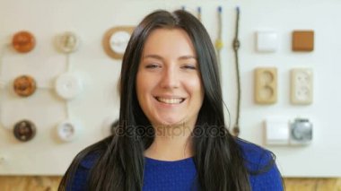 Gülümseyen ve kameraya priz ve anahtarları arka plan üzerinde seyir çekici kadın. Satıcı bir gömlek giymiş ve biraz anız vardır