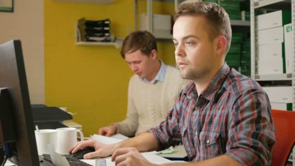 A young team of men working on a project in the office at the computer. Check the documents on taxes and fill out the electronic form. Teamwork to solve problems — Stock Video