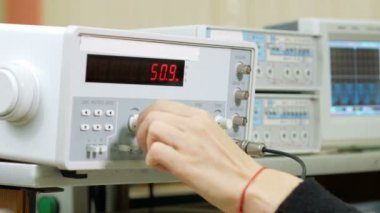 Kadın Mühendisi öğrenci elektrik jeneratörü el ile ayarlar. Cihaz ve dikkatle izlemek için göstergeler olusan değiştirir.
