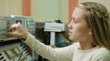 Genç kadın Mühendisi öğrenci laboratuarında elektrikli araçları ile çalışma. O dikkatle döner tekerlek saat ve endikasyonlar için arıyorsunuz