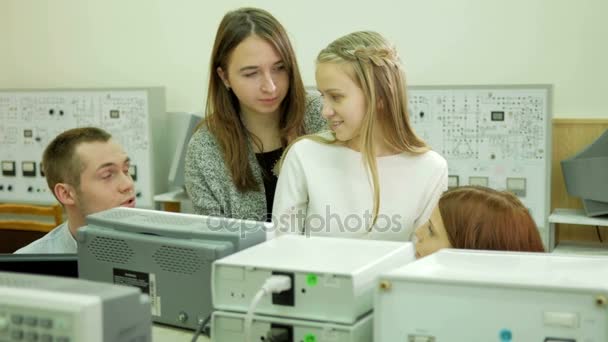 Jóvenes ingenieros estudiantiles trabajan en equipo en la Universidad del laboratorio eléctrico. Asesoran y prueban lecturas de voltímetro osciloscopio en los instrumentos. Futuros científicos — Vídeo de stock