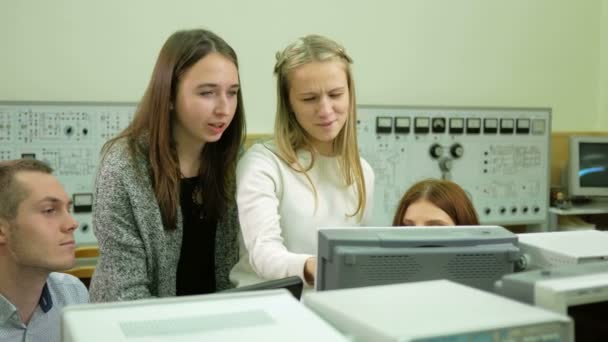 Fiatal mérnökök csapata Diákmunka az egyetemen az elektromos laboratóriumi. Tanácsot, és a teszt oszcilloszkóp voltmérő olvasmányok eszközöket. Jövőbeni tudósok — Stock videók