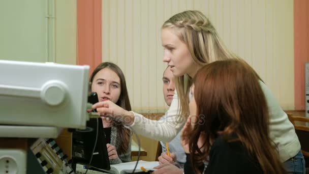 Jovens engenheiros estudantes trabalham em equipe na Universidade do laboratório elétrico. Eles aconselham e testam leituras de voltímetro de osciloscópio nos instrumentos. Futuros cientistas — Vídeo de Stock