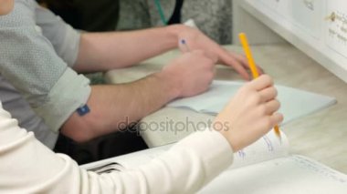 Bir grup öğrenci birlikte çalışan bir test cihazı Fizik Laboratuvarı. Birçok anahtarları ve ışıklar. Kadın ve erkek verilerini bir defterde yazar. Gelecekte bilim adamları