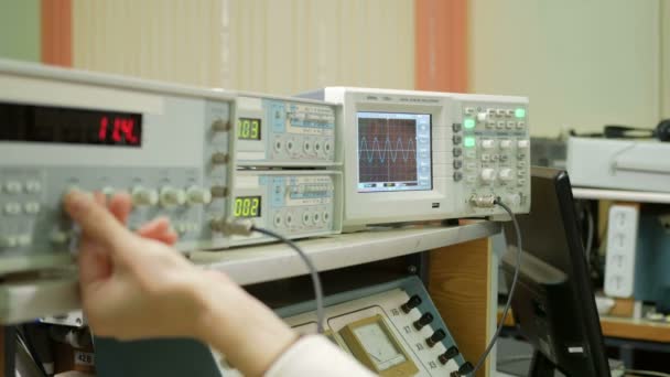 Обладнання для вимірювання електричних сигналів знаходиться у фізичній лабораторії. Табло запалювало дані приладів. Осцилограф і генератор імпульсів працюють разом . — стокове відео