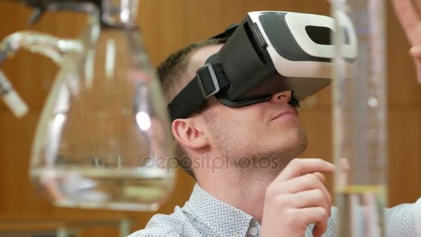 Giovane studente di sesso maschile con occhiali di realtà virtuale nel laboratorio chimico dell'Università. L'uomo vede la testa rotante modello 3D. futuro concetto di apprendimento — Video Stock