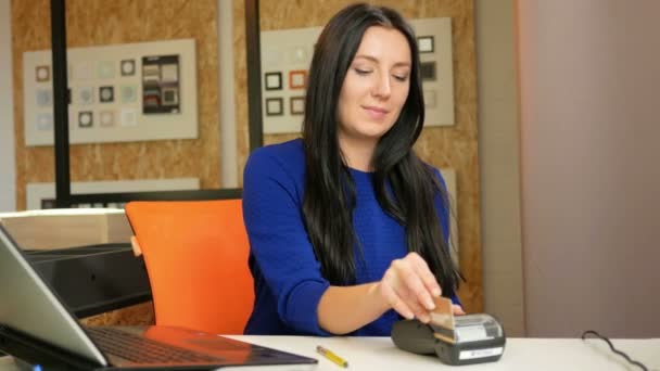 Attractive woman buying their own pay cards in the office using the terminal. She holds and pulls out a card payment slip. — Stock Video