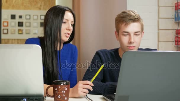 Красивая женщина консультирует мужчин по поводу проекта на ноутбуке в офисе. Он показывает палец на экране, который вы должны исправить. Концепция совместной работы в коворкинге — стоковое видео