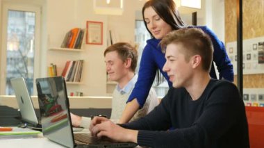 Güzel kız ofis içinde belgili tanımlık laptop projede hakkında erkeklerle danışır. Düzeltilmesi gereken ekranda bir parmağını gösterir. Coworking çalışmasında kavramı