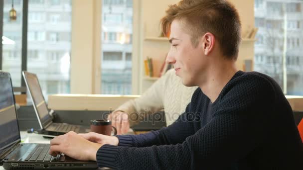 Genç proje laptoplarda ofiste çalışan adam ve yorgunluk nedeniyle çok gülmeye başlar. — Stok video