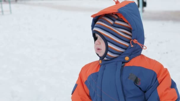 Piccolo bambino giocare nel parco giochi invernale e divertirsi con la neve. Stile di vita invernale concetto . — Video Stock