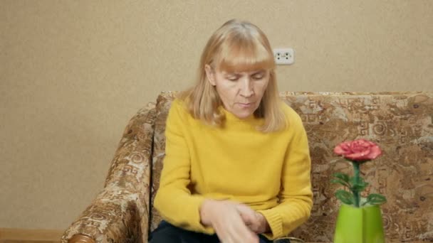 Sick senior woman taking pills in house on a sofa and drinks water in a glass. She makes several smooth liquid. The concept of health in the elderly — Stock Video
