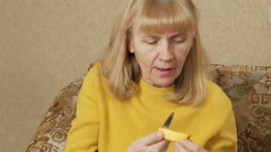 Kadınların yaş meyve evde kanepede yiyor. O kesikler Trabzon hurması bir parça kapalı ve tadını çıkarın. Sağlıklı gıda kavramı