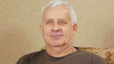 Adam evde kanepede oturan ve kameranın doğru seyir yaşta. Hes dürüst yüz. Yakın çekim