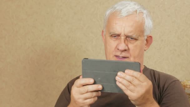 O homem com a idade do tablet se comunica com parentes na internet. Ele agita a mão e faz perguntas diferentes. para o conceito de comunicação na internet — Vídeo de Stock