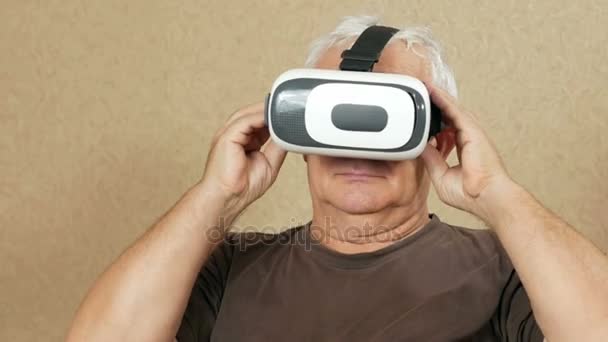 O homem usa óculos na idade da realidade virtual em casa no sofá. Ele balança a cabeça e quer tocar as mãos do que está acontecendo. Conceito de tecnologia futura — Vídeo de Stock