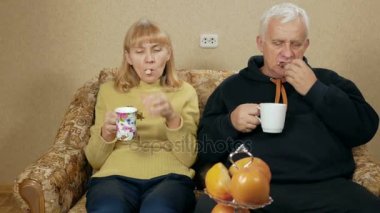 Yaşlı çift çay ve tatlı yemek. Karı koca evde kanepede ve rahatla, oturmak. tatil ev concept