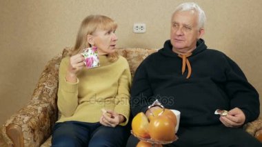 Yaşlı çift çay ve tatlı yemek. Karı koca evde kanepede ve rahatla, oturmak. tatil ev concept
