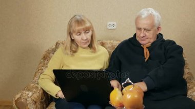 Yaşlı çift laptop ile çalışma hakkında bilgi edinin. Bir adam nasıl yapılacağını gösterir. Kadın gülüyor ve onu sonra tekrarlar. büyük insanların öğrenme kavramı