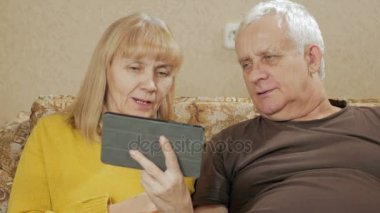 Yaşlı bir video golf sahası üstünde belgili tanımlık tablet halkaları kaç. Karı koca evde kanepede oturuyor. İletişim yakın akrabalar kavramı