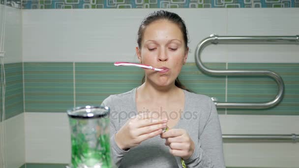 Молода приваблива жінка чистить зуби у ванній кімнаті готелю. Це викликає пасту на пензлі і дивиться на камеру — стокове відео