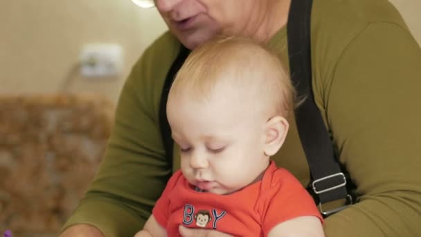 Ελκυστική μωρό σχέδιο με μαρκαδόρους σε χαρτί με τον παππού του. Το παιδί είναι αλλεργικό και κοκκινισμένα μάτια. Παιδί 1 έτους. — Αρχείο Βίντεο