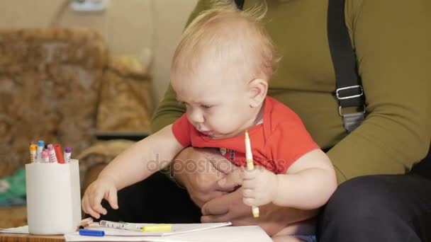Aantrekkelijke baby tekenen met markeringen op papier met zijn grootvader. Het kind allergisch is en rode ogen. Kind 1 jaar. — Stockvideo
