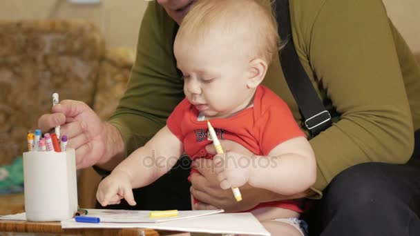 Attraktiva baby ritning med markörer på papper med sin farfar. Barnet är allergisk och rodnad ögon. Barn 1 år. — Stockvideo
