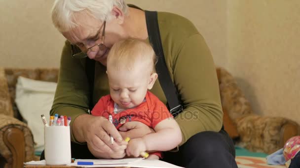 Attraktive Babyzeichnung mit Filzstiften auf Papier mit seinem Großvater. Das Kind ist allergisch und hat gerötete Augen. Kind 1 Jahr. — Stockvideo