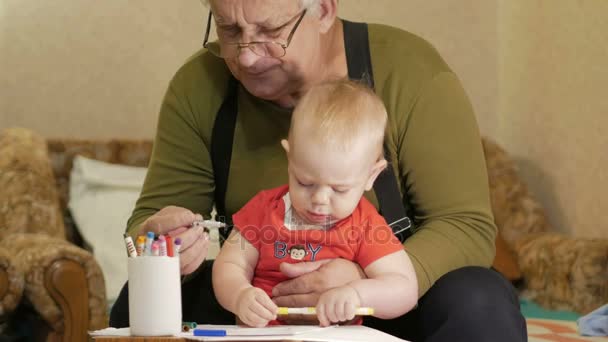 Attractive baby drawing with markers on paper with his grandfather. The child is allergic and reddened eyes. Kid 1 year. — Stock Video