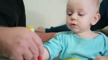 Çekici bir bebek bir kalem kanepede onun dedesi ile ev çizer. Çocuğun dedesi çekti hayvanlar dik dik bakıyor. Kuşakların kavramı