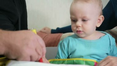 Çekici bir bebek bir kalem kanepede onun dedesi ile ev çizer. Çocuğun dedesi çekti hayvanlar dik dik bakıyor. Kuşakların kavramı