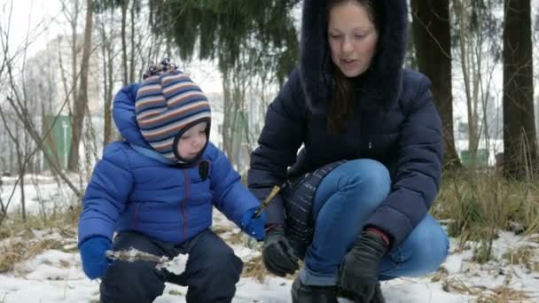 Bebê atraente brincando com a mãe no inverno fora na floresta. Mãe moldes para bolas de neve year-old boy — Vídeo de Stock