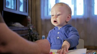 Dedesi onun torunu çocukla işaretleri kağıt üzerinde çizer. Çocuk dikkatle bakar ve yardım. Gülümseyen ve sürpriz. Öğretim çocuklar evde kavramının