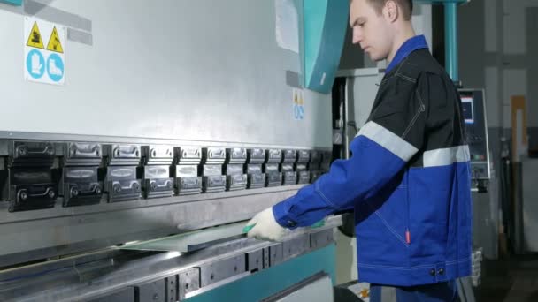 Hombre trabajando con chapa metálica en freno de prensa hidráulico CNC. Él pone la pieza y la dobla en una máquina grande en un ángulo — Vídeos de Stock