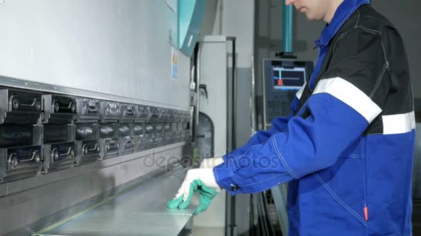 Hombre trabajando con chapa metálica en freno de prensa hidráulico CNC. Él pone la pieza y la dobla en una máquina grande en un ángulo — Vídeos de Stock