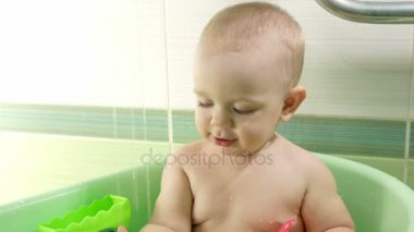 Banyo çekici bebek anne. Oğlan gülümsüyor ve renkli oyuncaklar ve su ile oynama. Yaklaşık bir yıl için çocuk