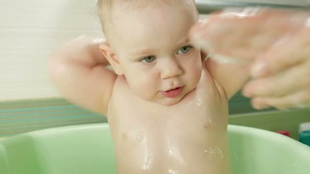 Feliz bebé tomando un baño jugando con burbujas de espuma. Madre lavando al niño. Un niño pequeño en una bañera. Niños sonrientes en el baño con juguetes. Padre e hijo juegan con agua . — Vídeo de stock