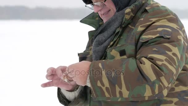 남자 얼음 낚시에 작은 물고기를 잡. 그는 선상에서 소요 하 고 얼음을 throw 합니다. 따뜻하게 입고 보호복 — 비디오