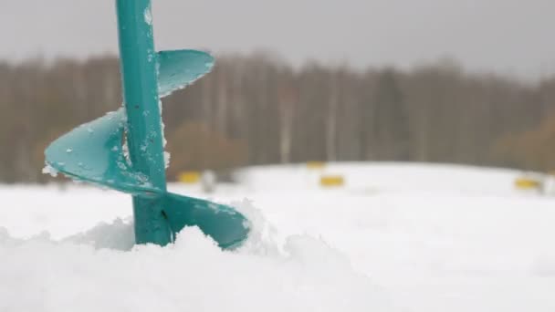 Borra ett hål för att göra is. Vatten hälls genom hålet. Sjö nära skogen i vinter — Stockvideo