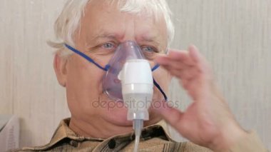 Astım bir maske evde tutan yaşlı bir adam. Nebulizatör ile solunum yolları iltihabı davranır. Astım ve öksürük engelliyor. Yakın çekim.