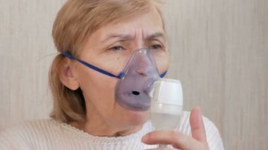 Astım bir maske evde tutan üst düzey kadın. Nebulizatör ile solunum yolları iltihabı davranır. Astım ve öksürük önlenmesi